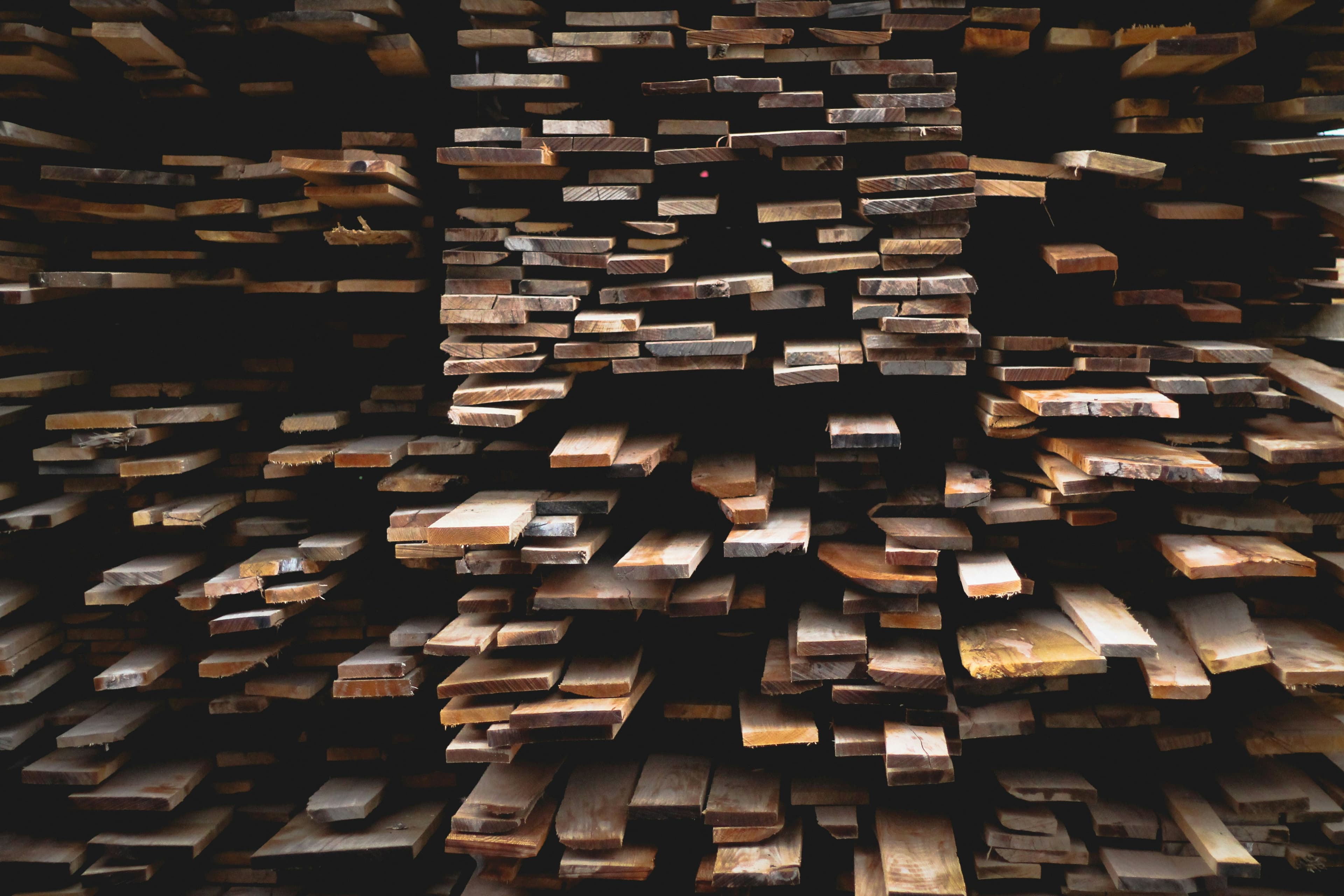 Backlit stack of cut timber boards in a yard